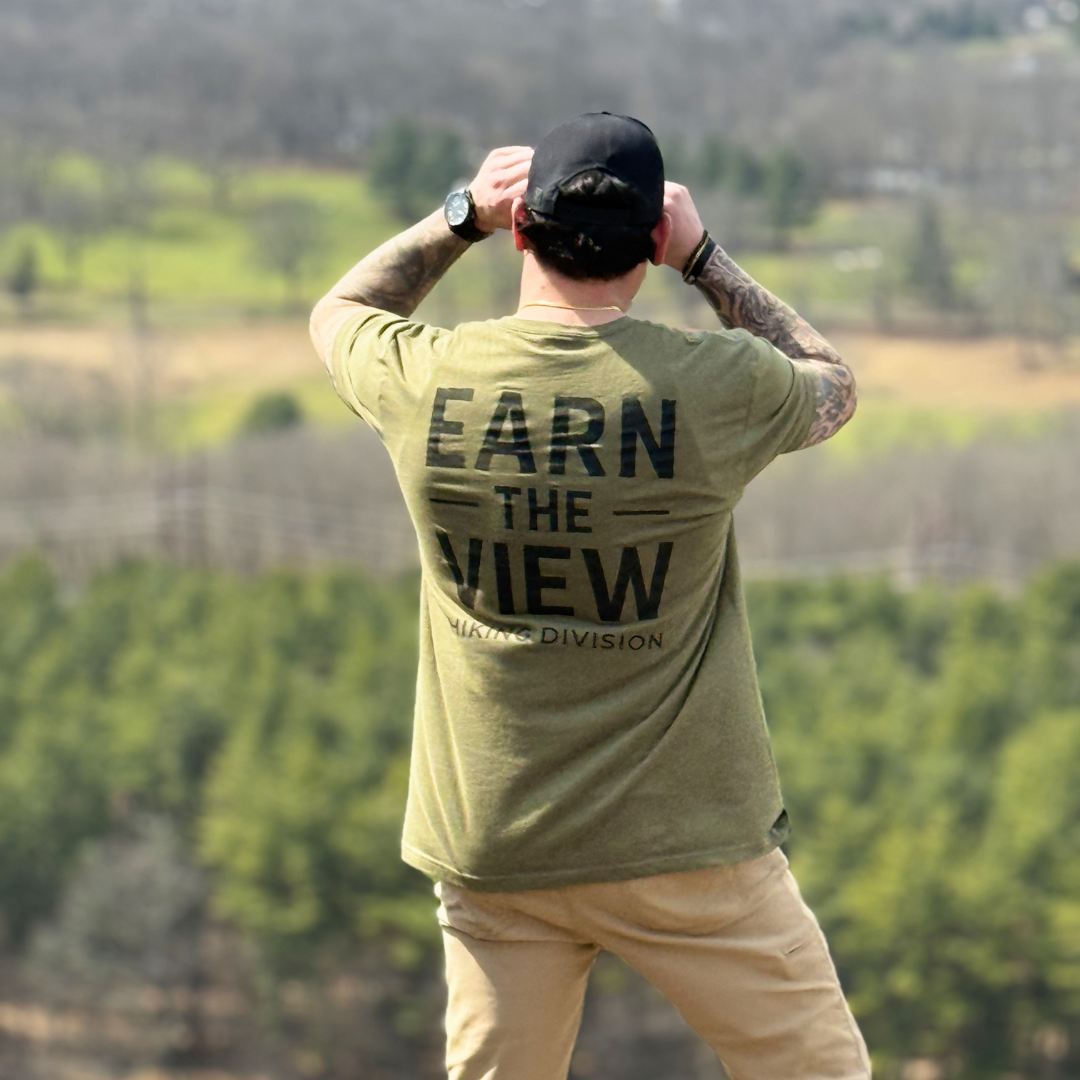 Man wearing a green t-shirt with 'Earn the View'  hiking division outdoor apparel 