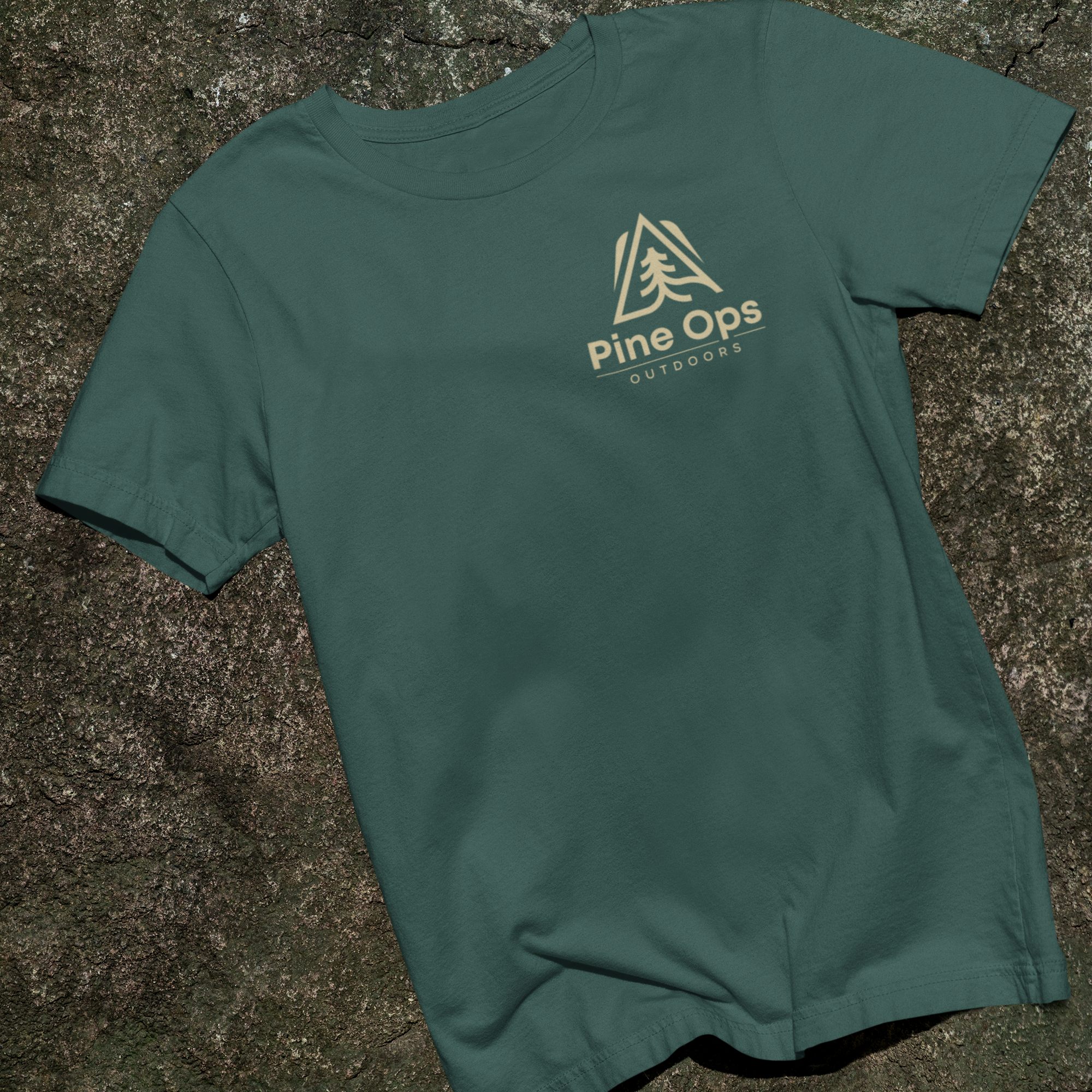 Green t-shirt with 'Pine Ops' logo on a stone surface